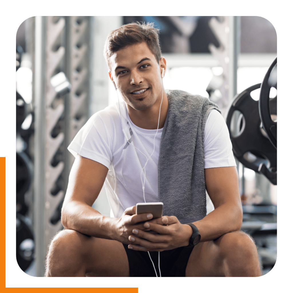 Happy man in the gym hitting a workout from an online training plan.