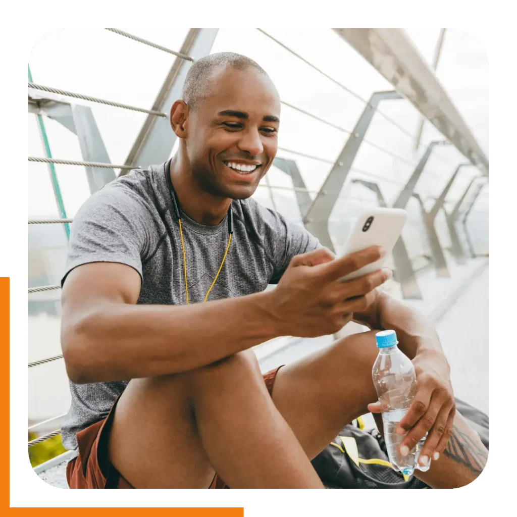 A male client smiling while checking his personalized workout plan online on his phone.