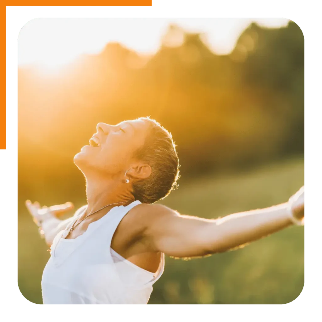 A happy woman celebrating her health journey with her arms open, an image that evokes the freedom and success of reaching her goals with an online nutrition coach.